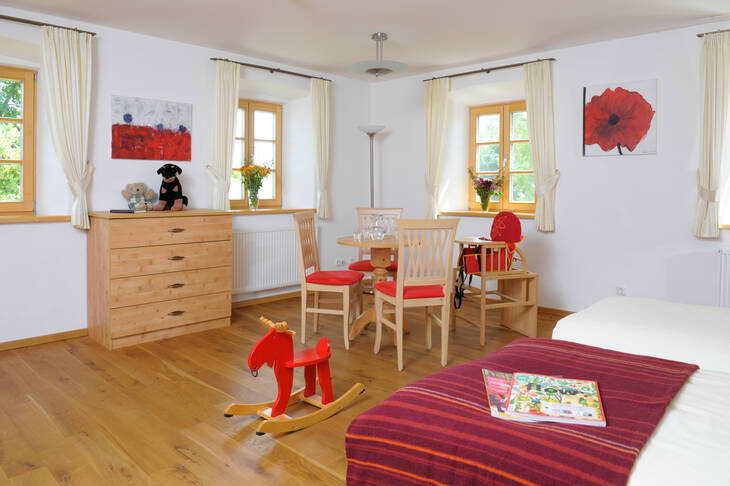 Familienzimmer im Irmengard-Hof mit Bett, Tisch und Schaukelpferd